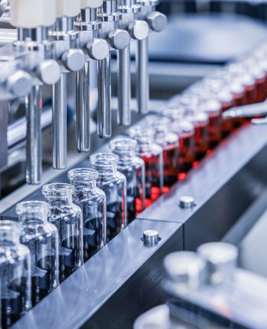 Vials of liquid getting filled by a machine